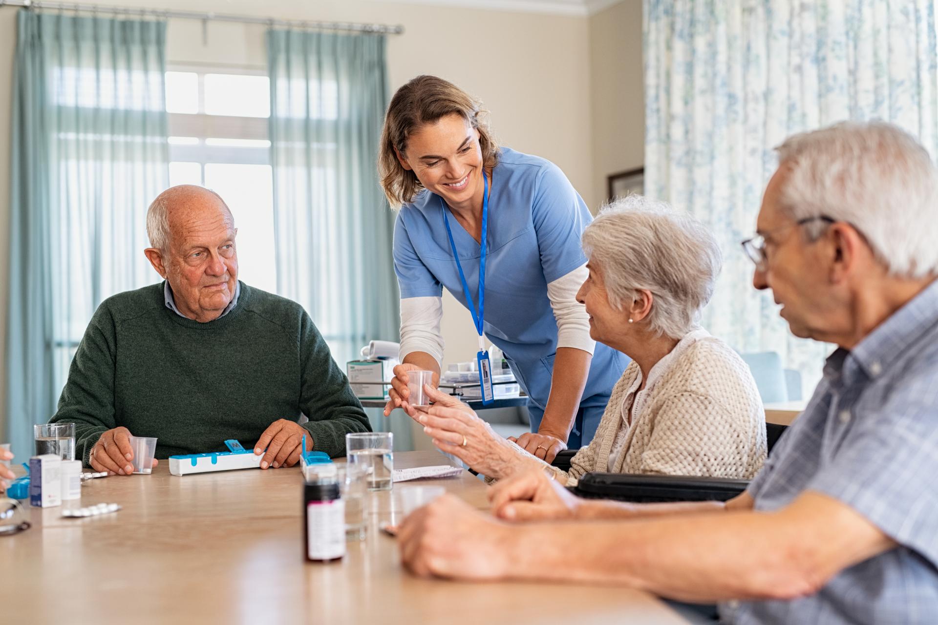 Lovely nurse giving medicine to senior woman at care facility